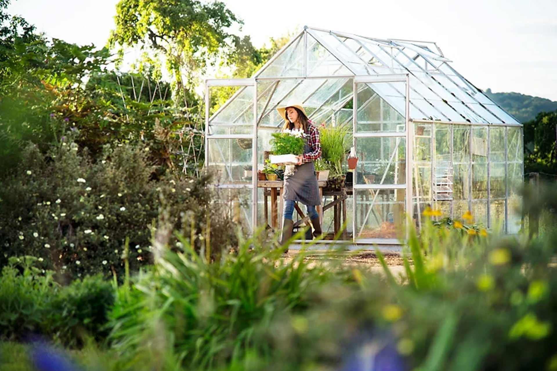 woman exiting a residential greenhouse depicting ways to reduce your carbon footprint