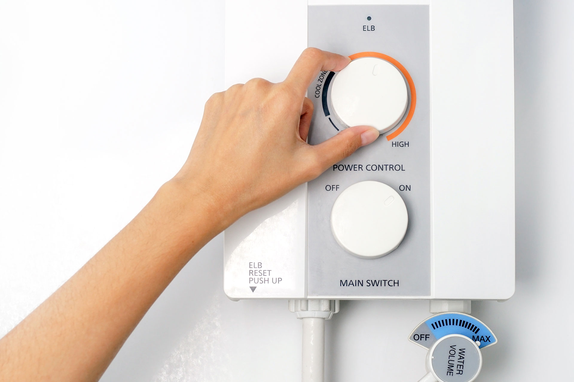 closeup of hand adjusting the temperature on a tankless hot water heater